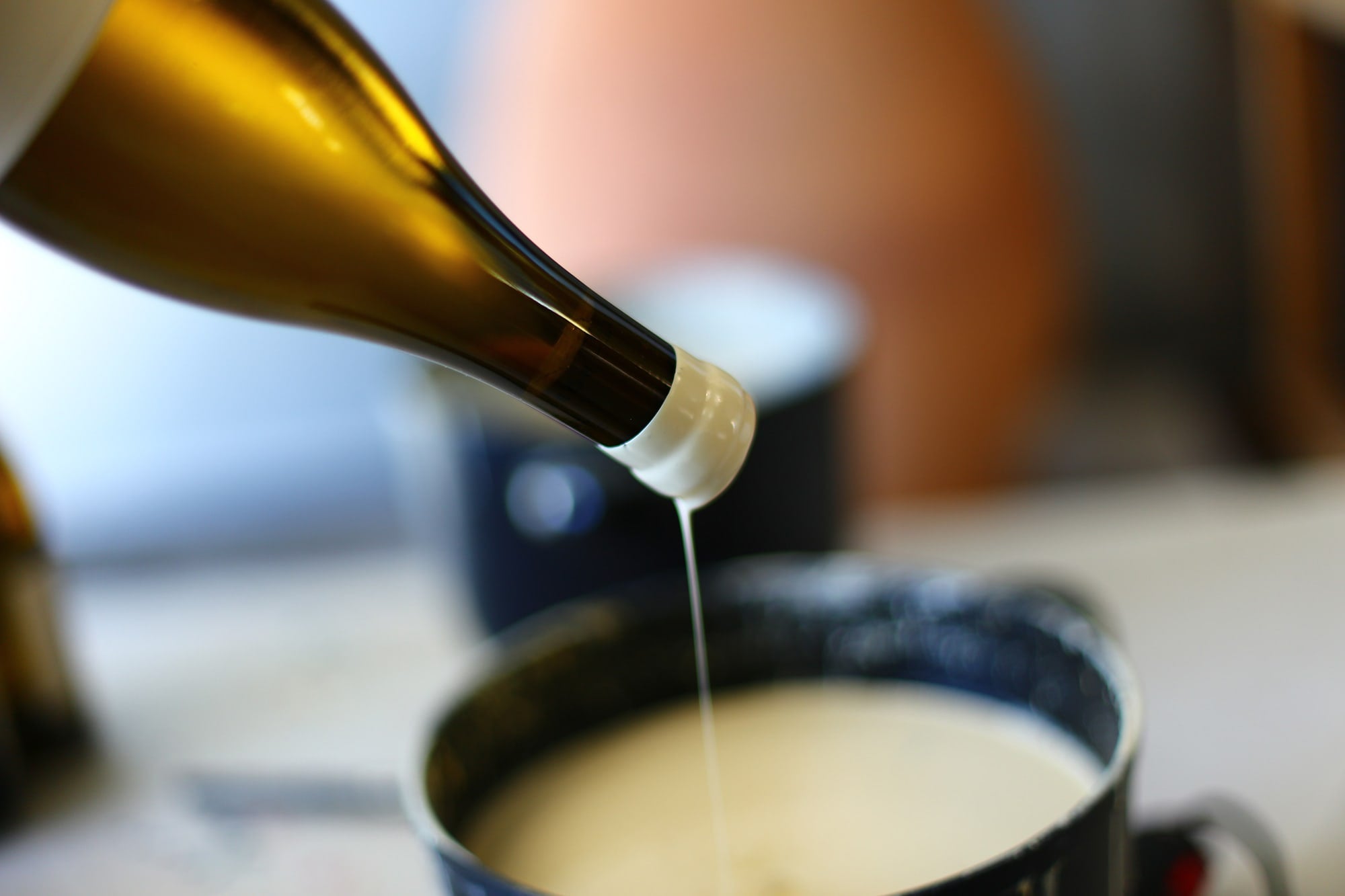 A close-up of a hand dipping a wine bottle neck into soft, melted wax at Arnot-Roberts winery, showcasing the final artisanal touch of California winemaking.
