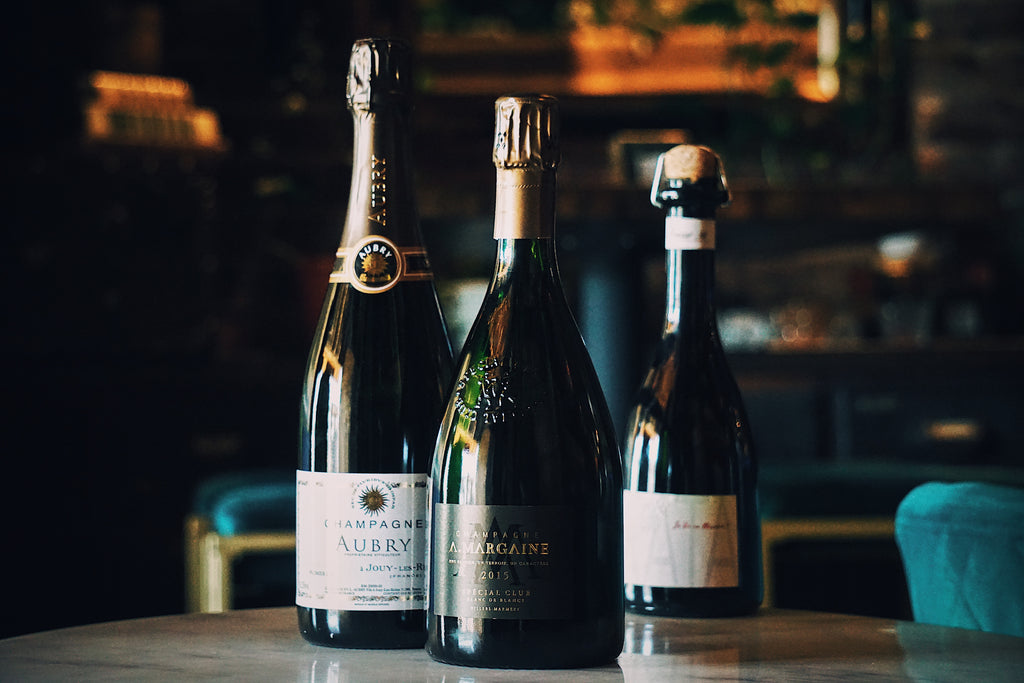 Two bottles of champagne, Aubry and Margaine, on a table with a blurred background.