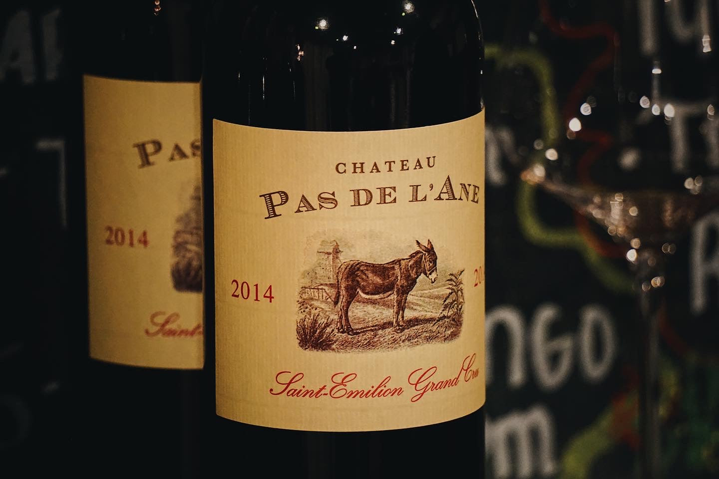 Wine bottle labeled 'Chateau Pas de l'Ane' with a donkey illustration on a dark background.