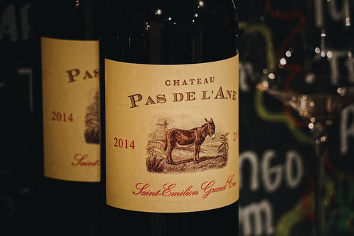 Wine bottle labeled 'Chateau Pas de l'Ane' with a donkey illustration on a dark background.