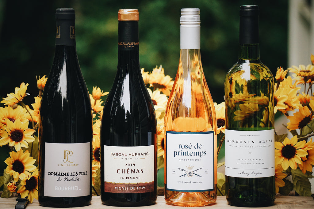 Four organic French wine bottles with labels in front of sunflower flowers