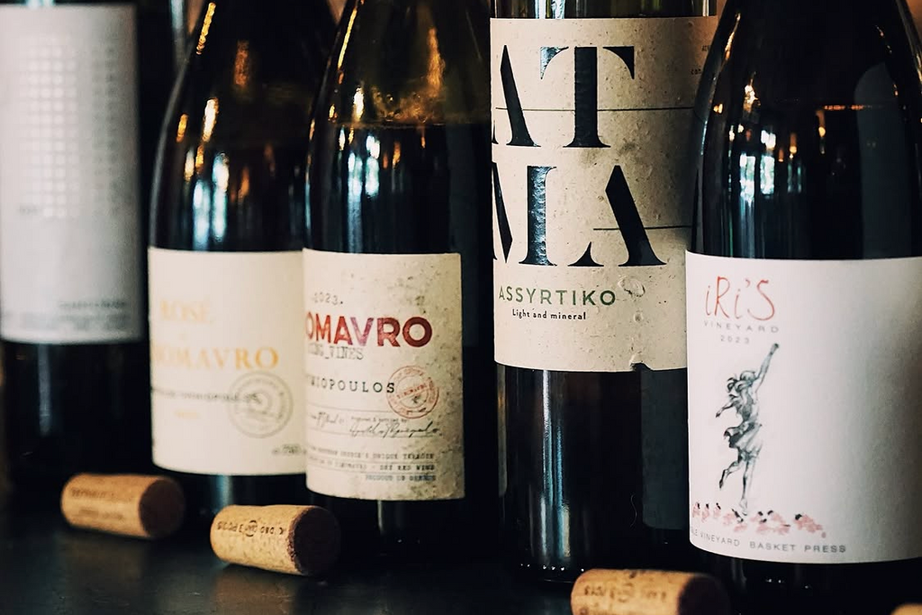 Collection of Greek wine bottles with visible labels on a dark surface.