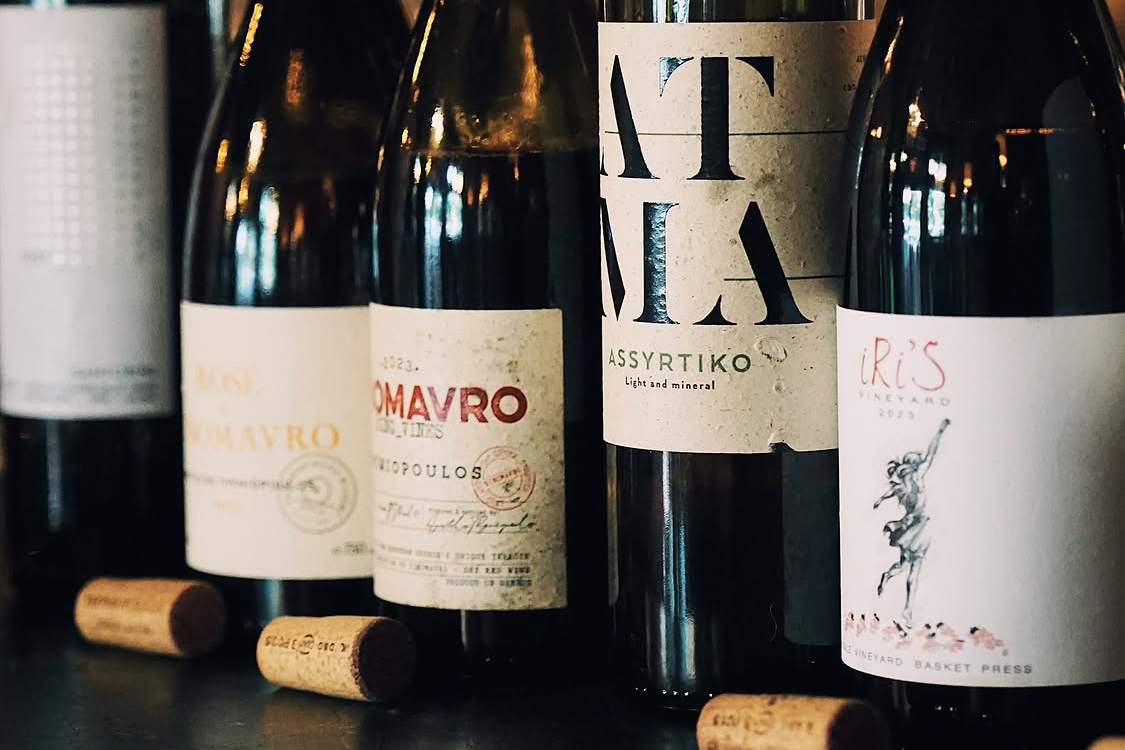 Collection of Greek wine bottles with visible labels on a dark surface.