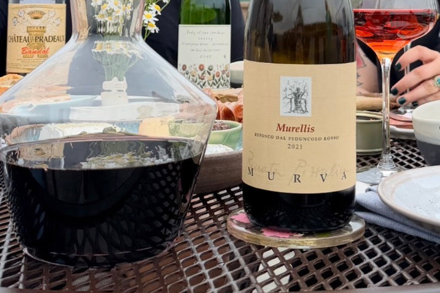 Wine bottle labeled 'Murellis' on a table with a decanter and glasses.