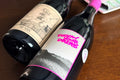 Two wine bottles on a wooden surface with visible labels.